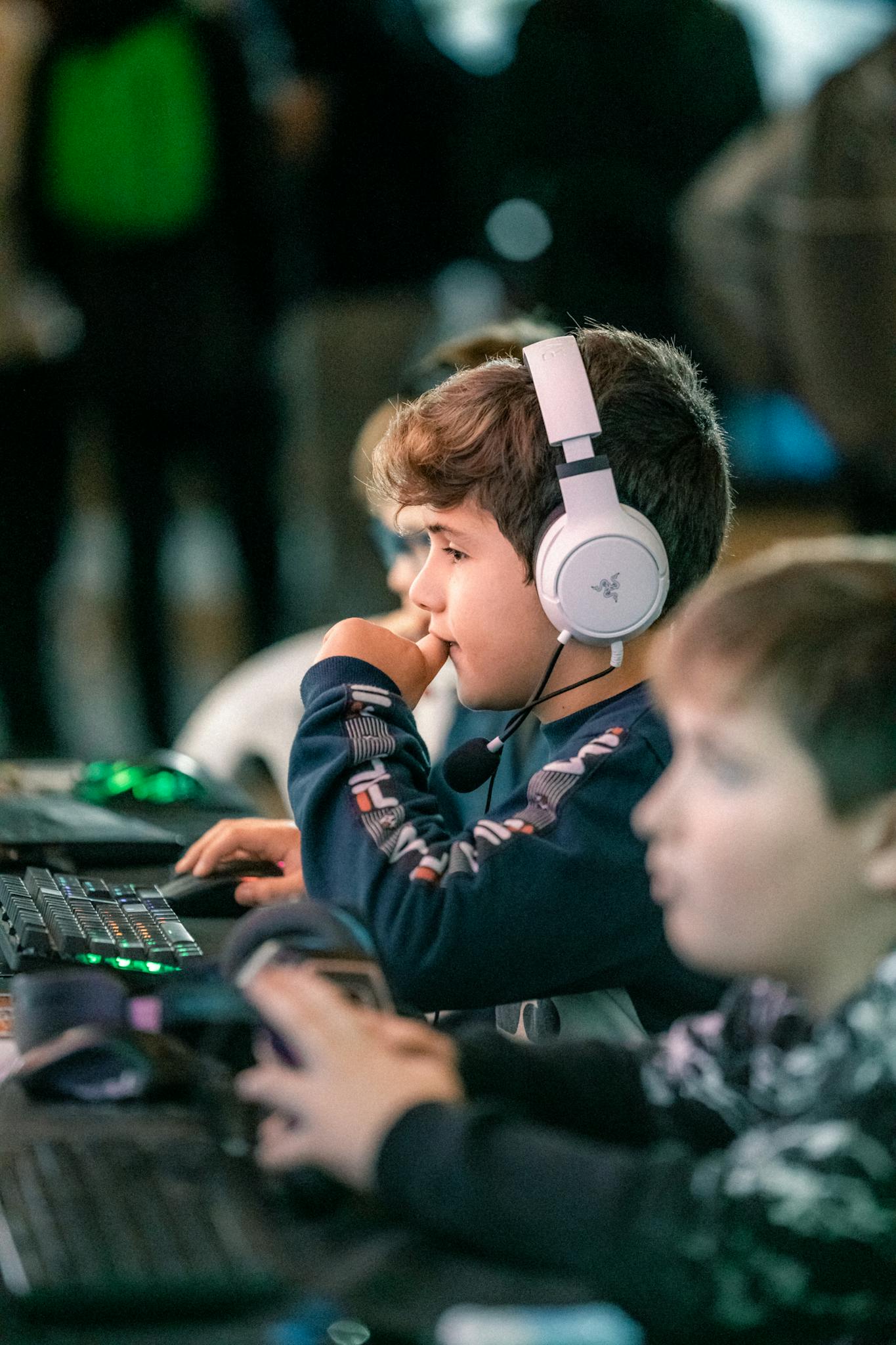Children engaged in gaming at a computer event, showcasing teamwork and focus.